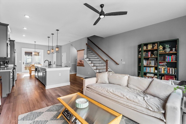 living room featuring sink, dark wood-type flooring, and ceiling fan with notable chandelier