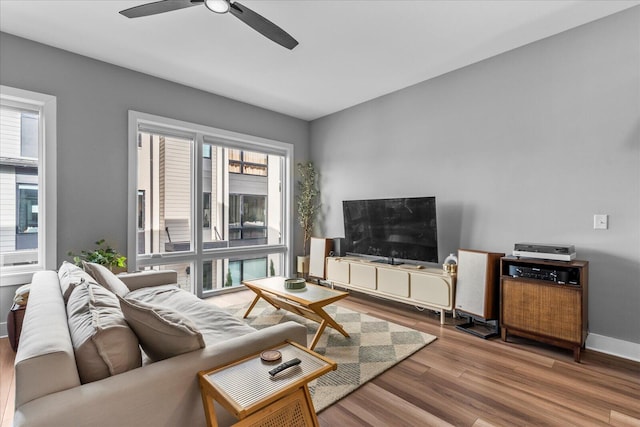 living room with wood-type flooring, ceiling fan, and a healthy amount of sunlight