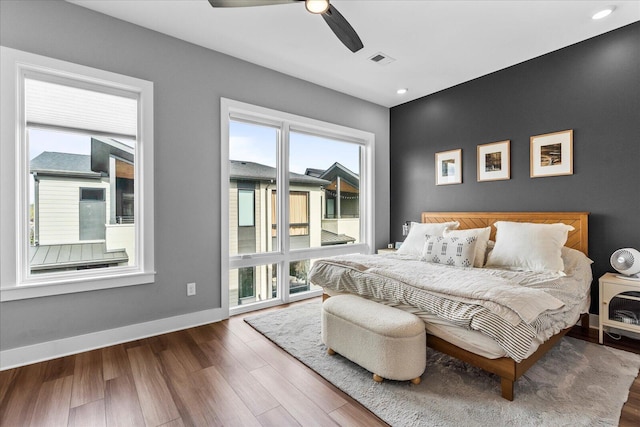 bedroom with multiple windows, ceiling fan, and hardwood / wood-style floors