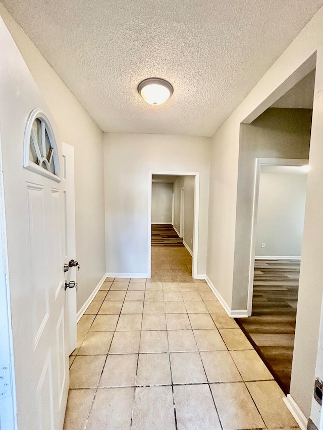 corridor with a textured ceiling and light tile patterned floors