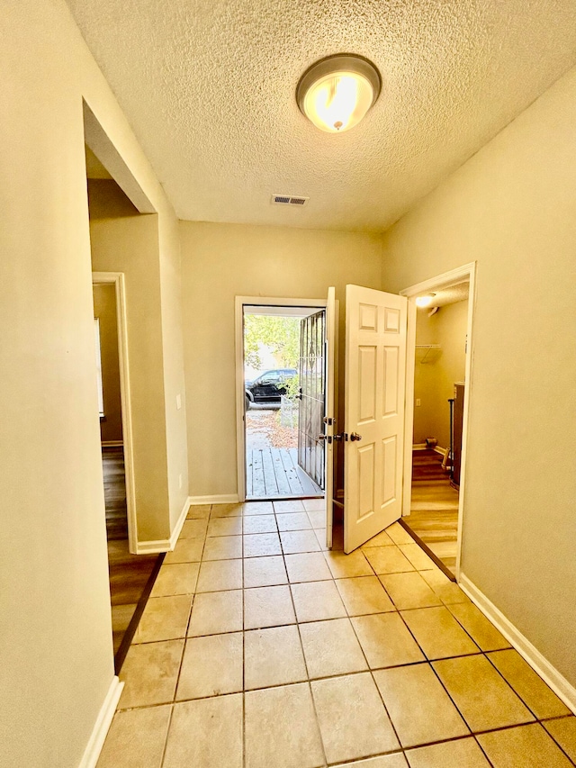 hall featuring light hardwood / wood-style floors and a textured ceiling