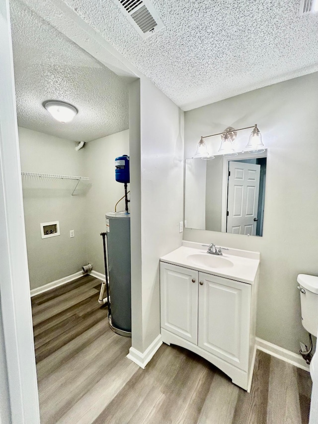 bathroom with hardwood / wood-style floors, a textured ceiling, toilet, and vanity