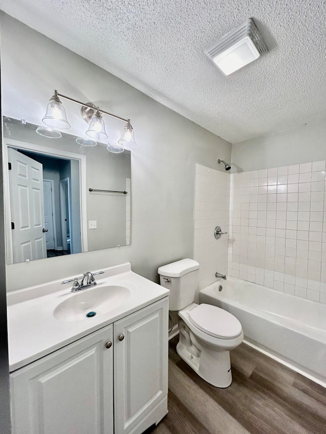 full bathroom with vanity, a textured ceiling, bathtub / shower combination, hardwood / wood-style flooring, and toilet