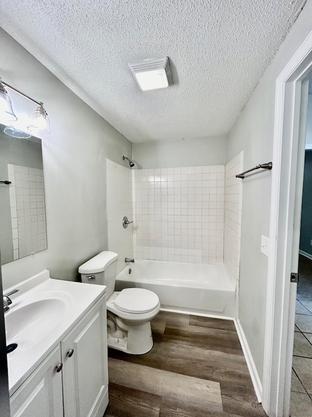 full bathroom with toilet, hardwood / wood-style floors, tiled shower / bath, a textured ceiling, and vanity