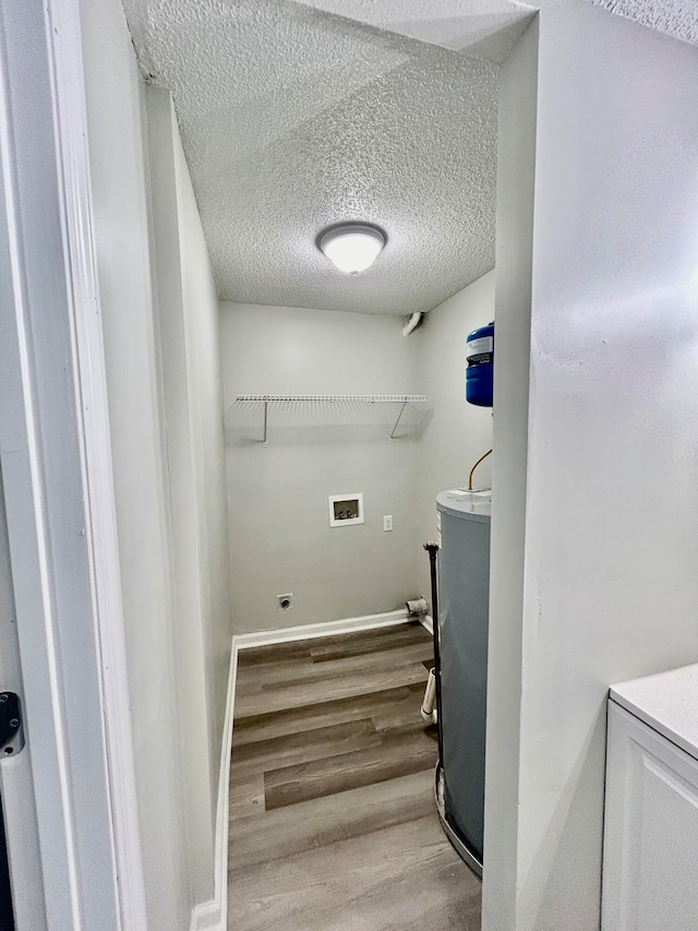 washroom featuring wood-type flooring, hookup for a washing machine, a textured ceiling, and water heater