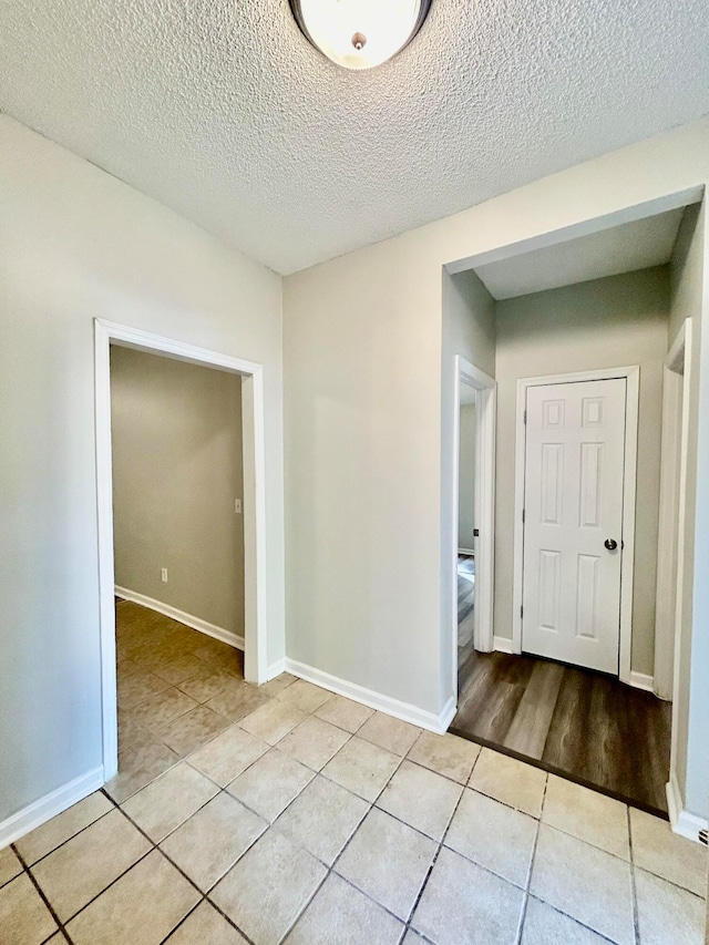 empty room featuring a textured ceiling and light tile patterned floors