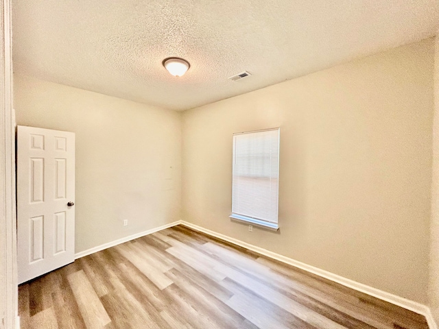 unfurnished room with wood-type flooring and a textured ceiling