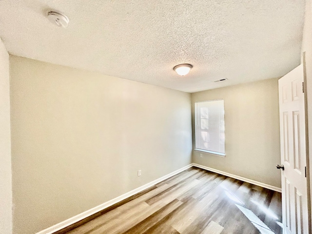 empty room featuring a textured ceiling and hardwood / wood-style flooring