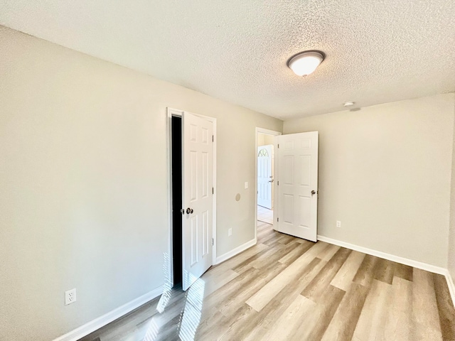 unfurnished room featuring light wood-type flooring and a textured ceiling