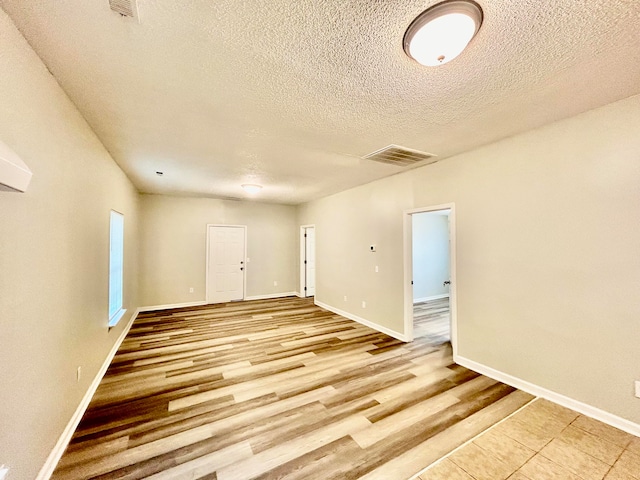 empty room with a textured ceiling and light hardwood / wood-style flooring