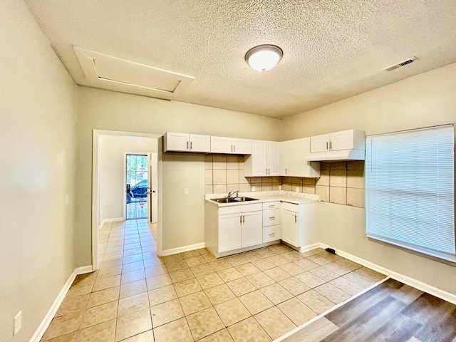 kitchen featuring light tile patterned flooring, white cabinetry, a textured ceiling, sink, and decorative backsplash