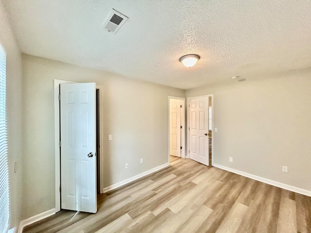 unfurnished room with a textured ceiling and light hardwood / wood-style floors