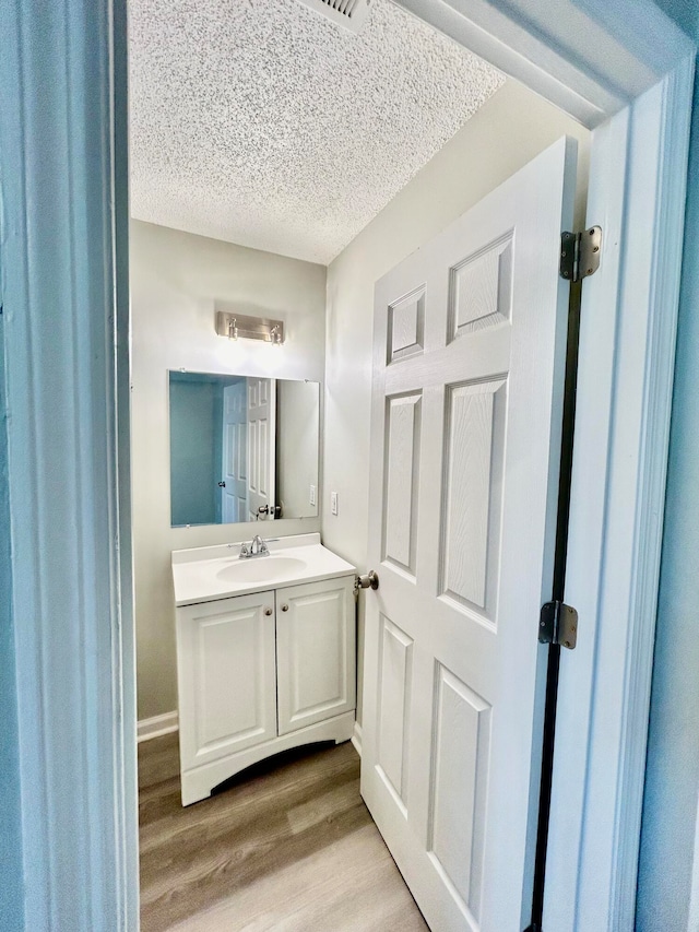 bathroom with vanity, a textured ceiling, and hardwood / wood-style flooring