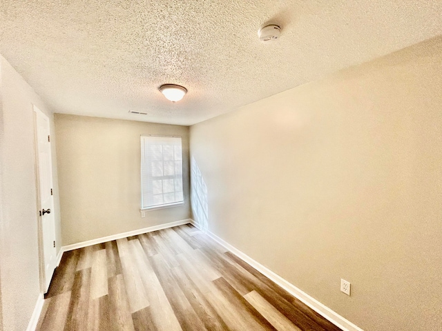 empty room with wood-type flooring and a textured ceiling