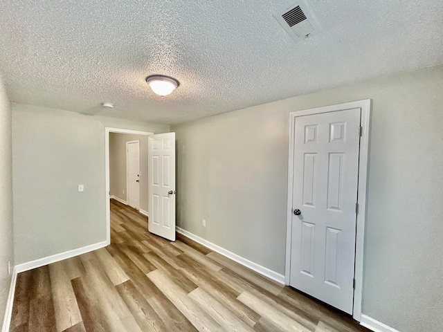 spare room featuring a textured ceiling and light hardwood / wood-style flooring