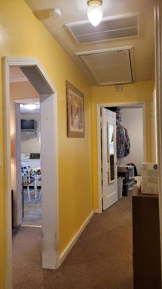 hall with a textured ceiling and carpet floors