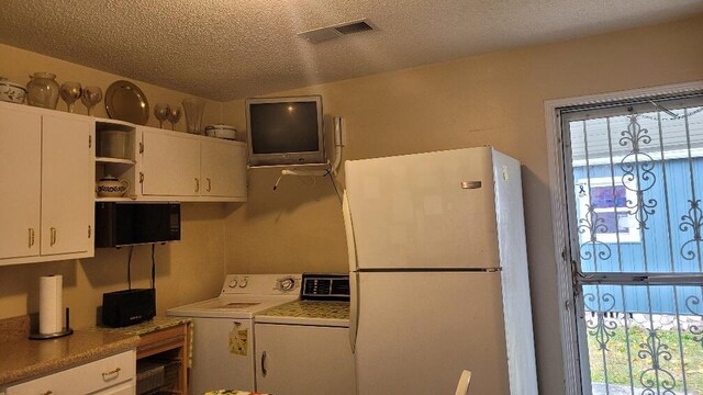 kitchen featuring white refrigerator, white cabinetry, a textured ceiling, and washer / clothes dryer