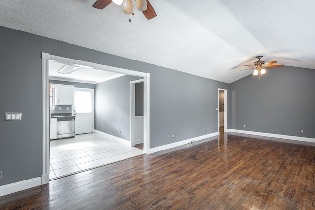 unfurnished living room with a textured ceiling, ceiling fan, lofted ceiling, and light wood-type flooring