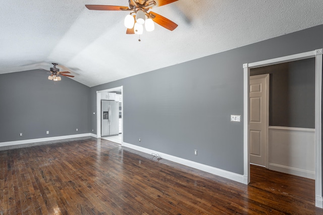 empty room with ceiling fan, lofted ceiling, dark hardwood / wood-style flooring, and a textured ceiling