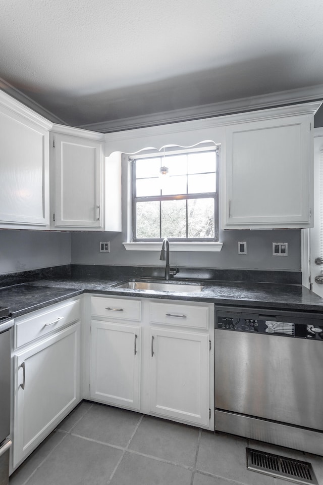 kitchen featuring white cabinets, light tile patterned floors, stainless steel dishwasher, and sink