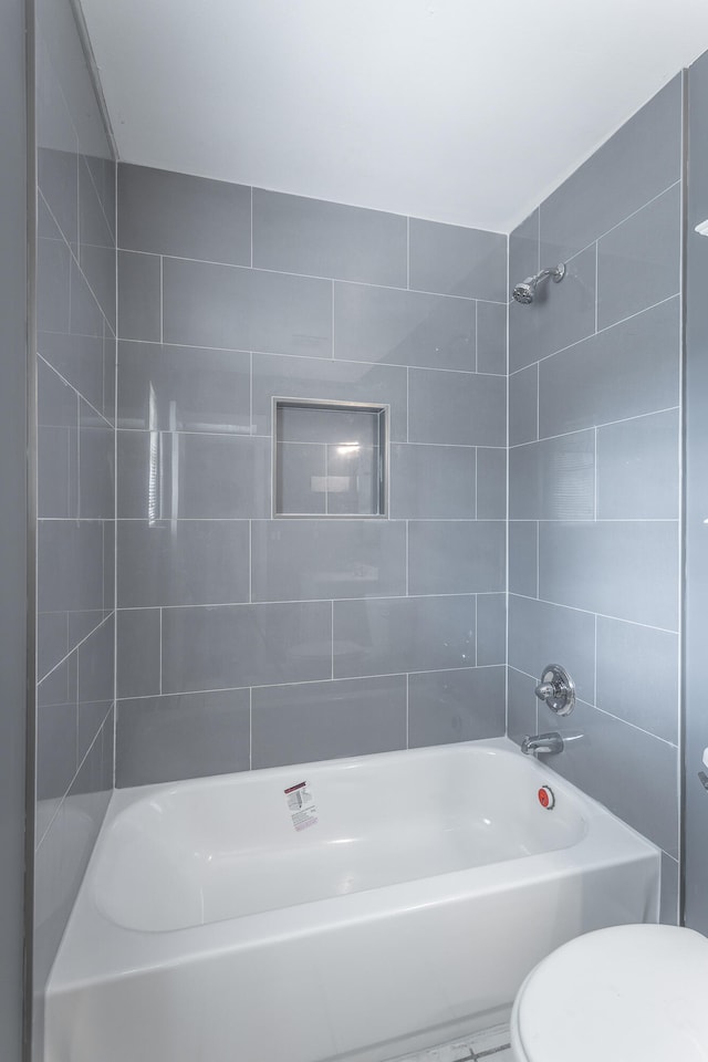 bathroom with tiled shower / bath combo and toilet