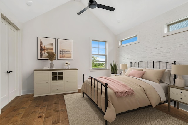 bedroom with ceiling fan, dark hardwood / wood-style flooring, high vaulted ceiling, and brick wall