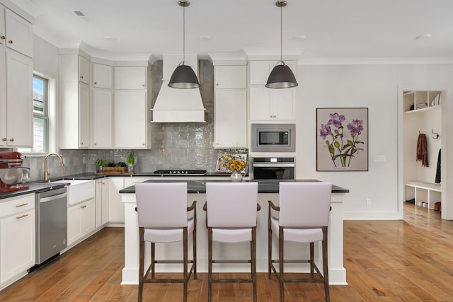 kitchen with custom exhaust hood, a kitchen island, light hardwood / wood-style floors, and appliances with stainless steel finishes