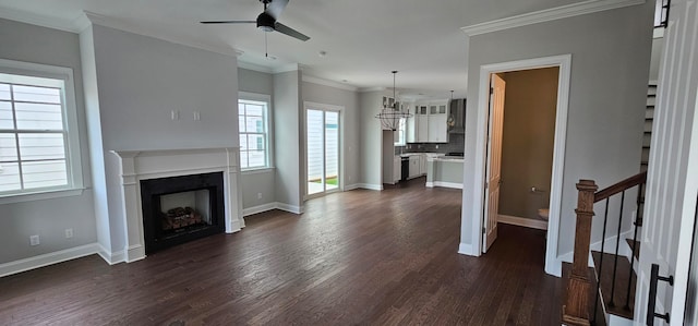 unfurnished living room featuring ceiling fan with notable chandelier, crown molding, and dark wood-type flooring