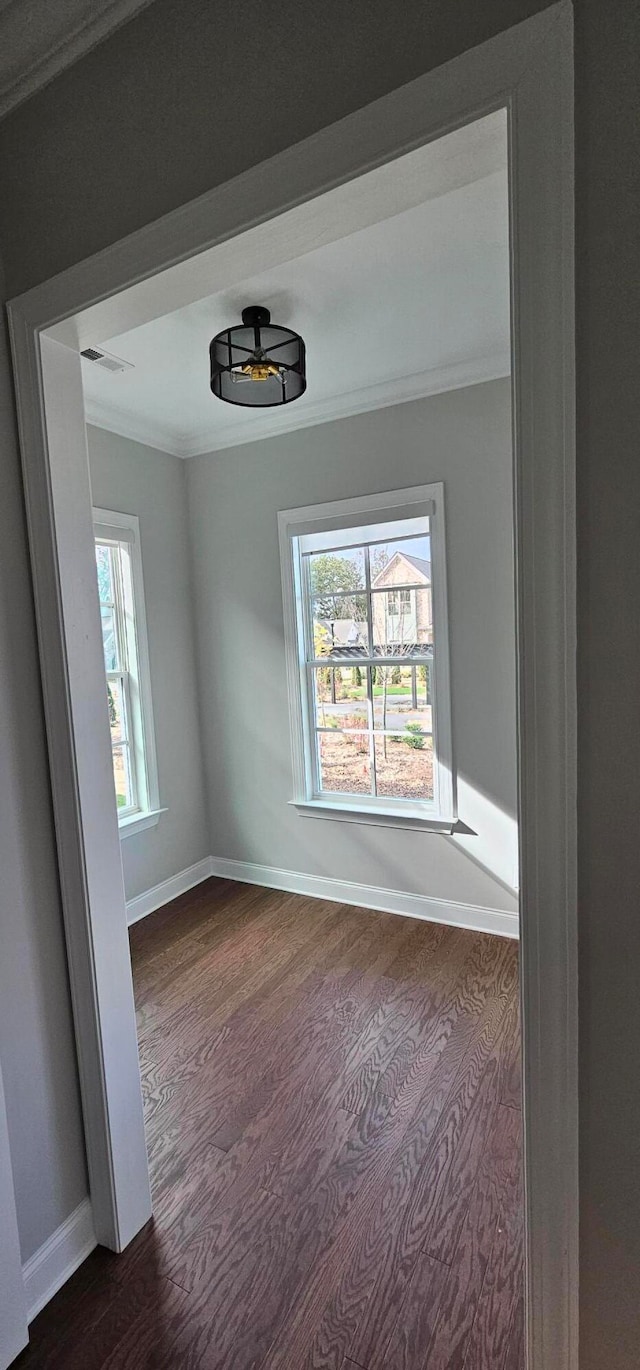 empty room featuring dark wood-type flooring and ornamental molding