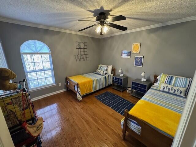 bedroom featuring wood-type flooring, a textured ceiling, ceiling fan, and crown molding