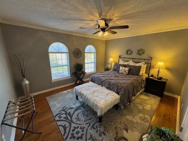 bedroom featuring ceiling fan, crown molding, dark wood-type flooring, and a textured ceiling