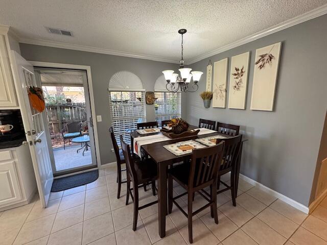 tiled dining room featuring a textured ceiling, ornamental molding, and a notable chandelier