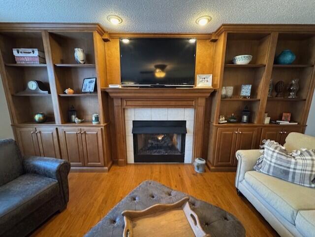 living room with light wood-style flooring, a fireplace, and a textured ceiling