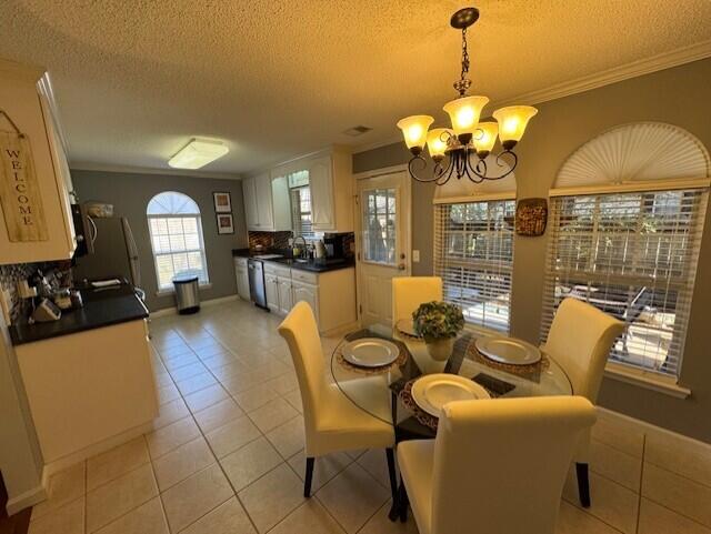 dining area featuring light tile patterned floors, ornamental molding, a chandelier, and a textured ceiling