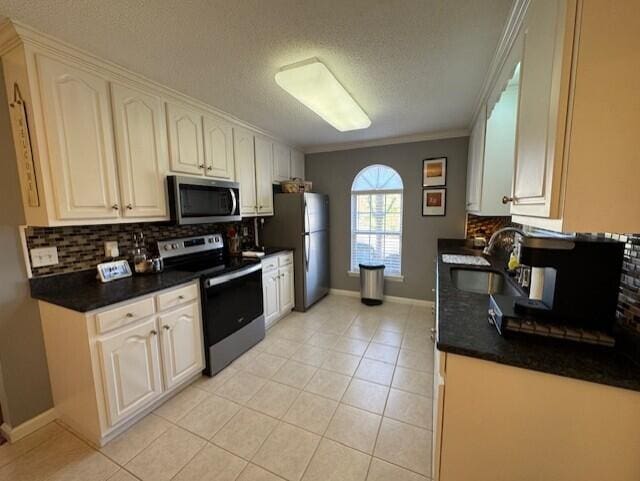 kitchen featuring light tile patterned floors, decorative backsplash, dark countertops, stainless steel appliances, and a sink