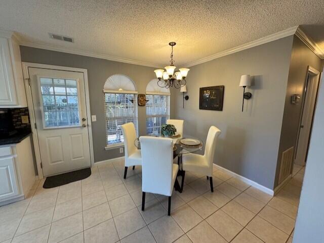 dining space with a wealth of natural light, ornamental molding, visible vents, and an inviting chandelier