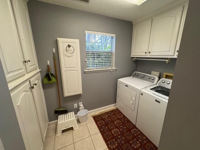 washroom with light tile patterned floors, cabinet space, a textured ceiling, independent washer and dryer, and baseboards