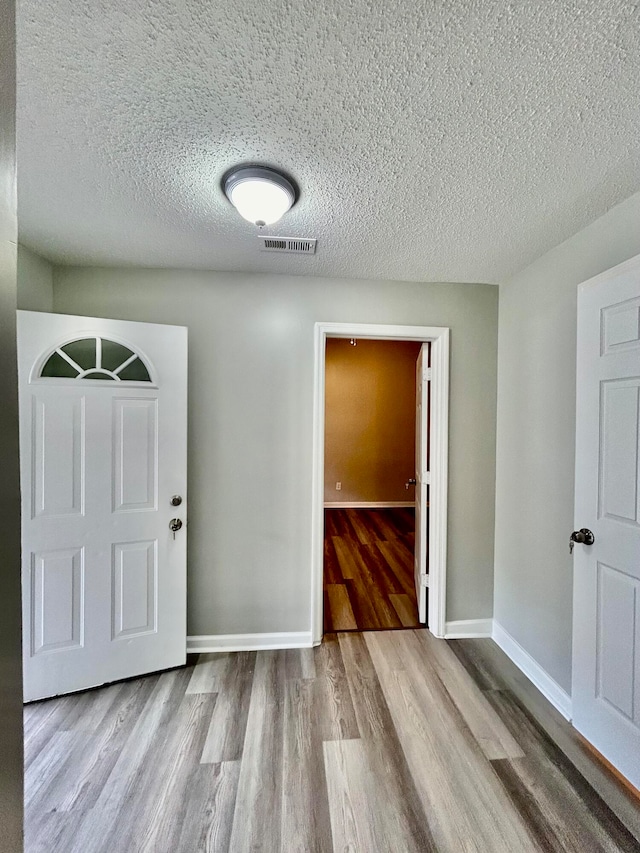 foyer entrance with light wood-type flooring and a textured ceiling