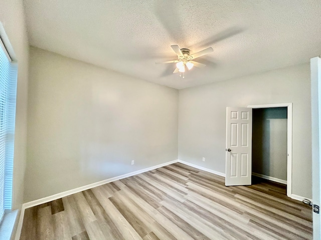 unfurnished bedroom featuring light wood-type flooring, a textured ceiling, and ceiling fan