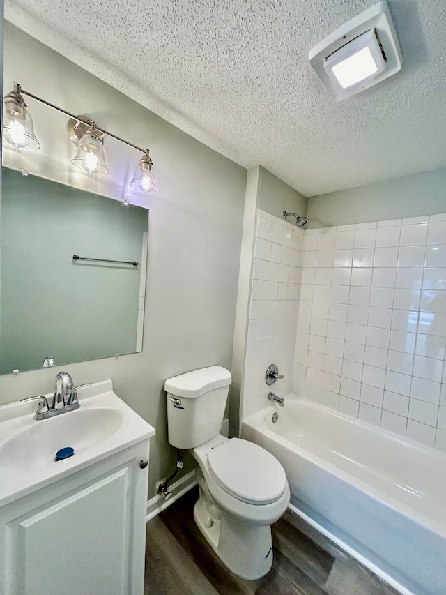 full bathroom featuring wood-type flooring, vanity, a textured ceiling, tiled shower / bath combo, and toilet