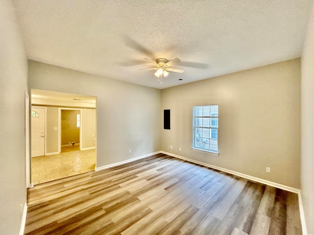 spare room featuring light wood-type flooring, a textured ceiling, and ceiling fan