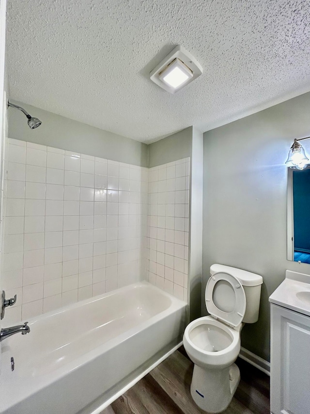 full bathroom with tiled shower / bath, a textured ceiling, wood-type flooring, vanity, and toilet