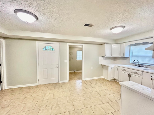 kitchen with white cabinets, light tile patterned flooring, a textured ceiling, and sink