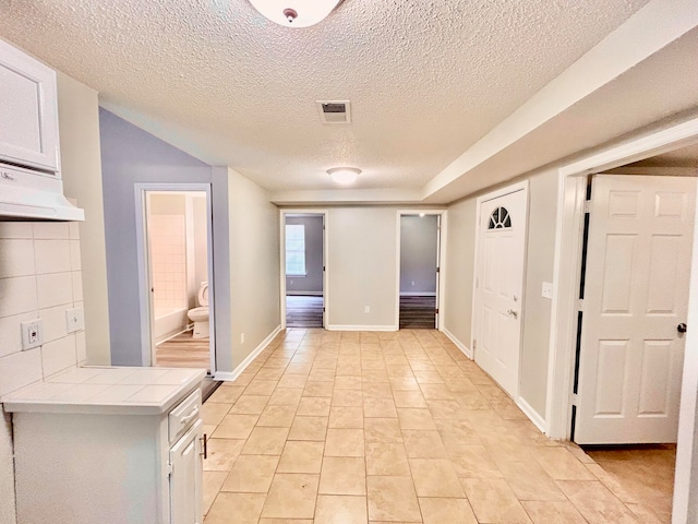 hall featuring light tile patterned flooring and a textured ceiling