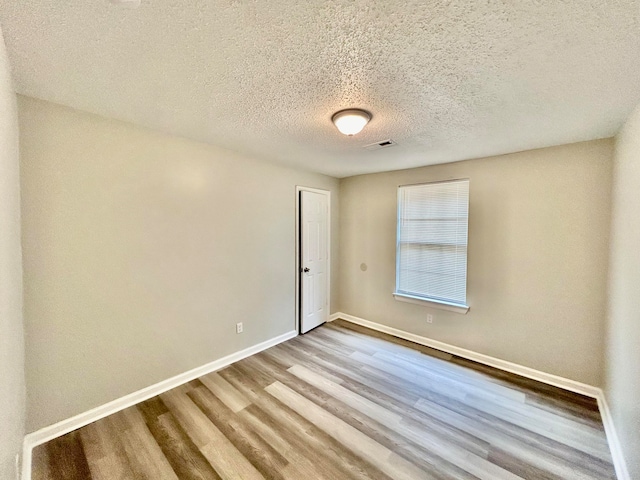 unfurnished room with a textured ceiling and hardwood / wood-style flooring