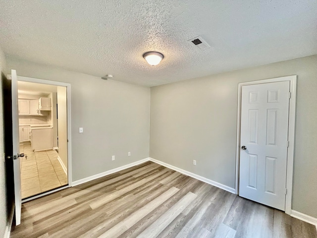 unfurnished bedroom featuring light wood-type flooring and a textured ceiling