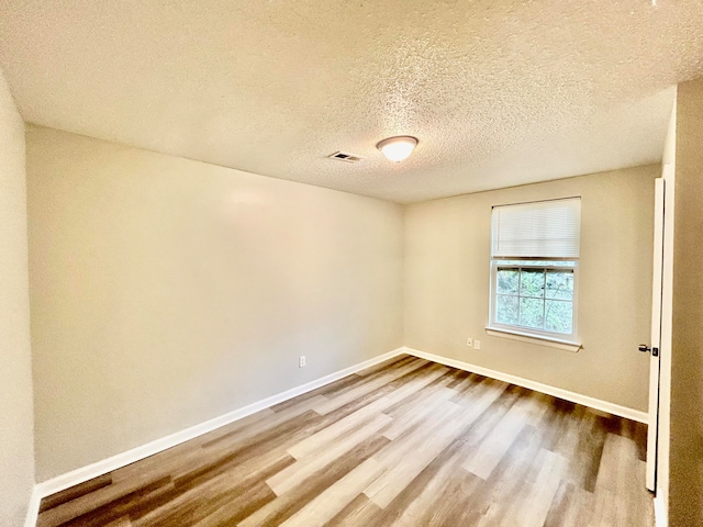 unfurnished room featuring wood-type flooring and a textured ceiling