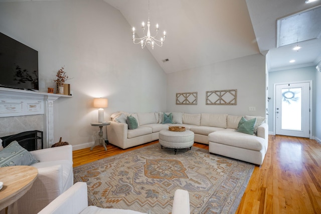 living room with high vaulted ceiling, a high end fireplace, a notable chandelier, and hardwood / wood-style flooring