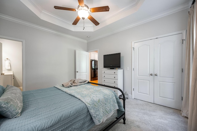 bedroom with ceiling fan, light colored carpet, a closet, and a raised ceiling