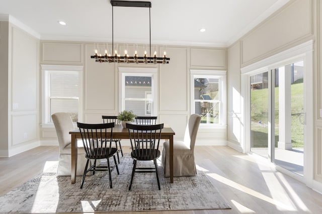 dining area with light hardwood / wood-style floors, ornamental molding, and a chandelier